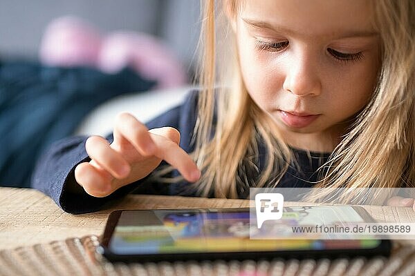 Mädchen mit Smartphone auf Sofa. Kinder und Technologie Konzept