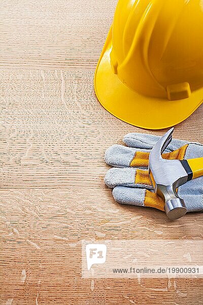 Gelber Helm Schutzhandschuh Klauenhammer auf Holzbrett Baukonzept