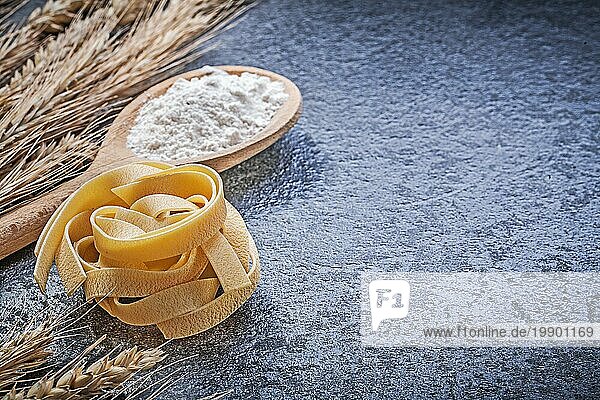 Goldener Weizen Roggen Ohren Holzlöffel Mehl lang geschnittene gedrehte Makkaroni auf schwarzem Hintergrund Essen und Trinken Konzept