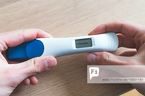 Frau hält Schwangerschaftstest in der Hand  Ergebnis ist schwanger  ?Schwanger?