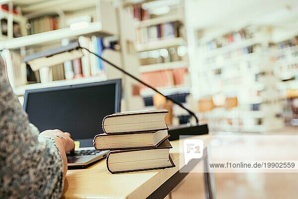 Blonde Studentin sitzt am Schreibtisch mit Stapel von Büchern  Universitätsbibliothek