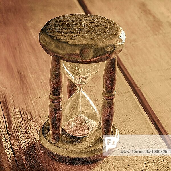 Zeit Konzept. Ein Vintage Sanduhr mit Sand fallen durch  auf einem rustikalen Hintergrund  getönten quadratisches Bild