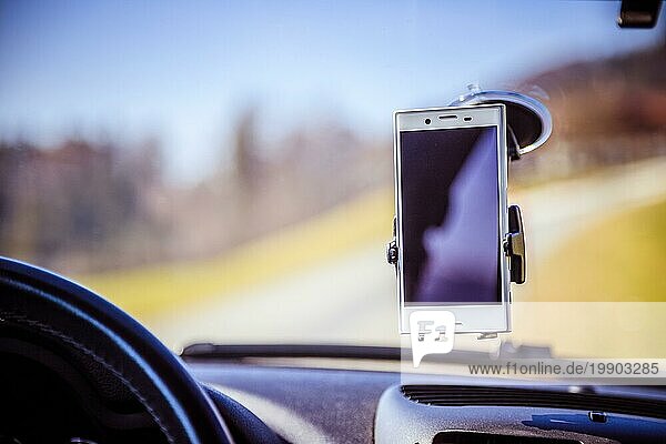 Innenraum eines modernen Autos an einem sonnigen Tag. Smartphone auf mobiler Halterung  verwendet als Navigationsgerät