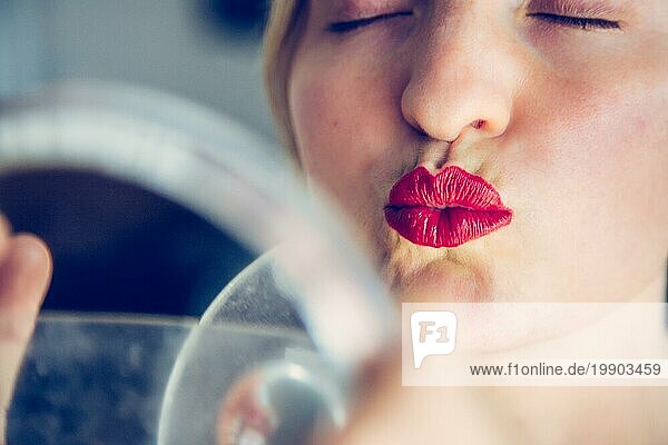 Hübsche weiße Frau mit roten sinnlichen Lippenstift und bunten Nagellack ist in den Spiegel schauen  Kussmund