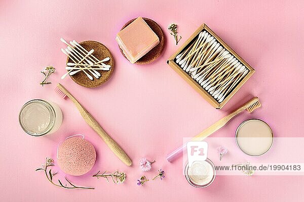 Plastikfreie  abfallfreie Kosmetika  flach gelegt auf einem rosa Hintergrund. Zahnbürsten aus Bambus und Wattestäbchen  Konjac Schwamm  die einen Rahmen mit Platz für Text bilden
