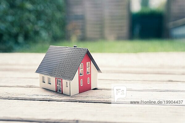 Rotes Hausmodell auf dem Boden  im Freien. Konzept für neues Haus  Grundstück und Anwesen