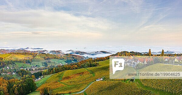 Südsteirische Weinbergslandschaft  Luftbild vom Eckberg mit herbstlichen Weinbergen und nebligen Alpen in der Ferne