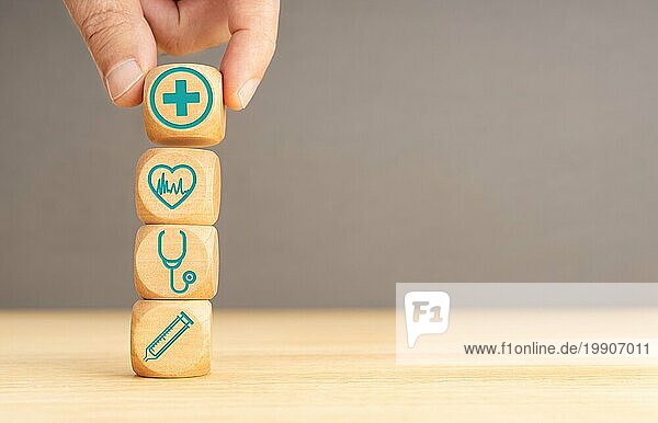 Krankenversicherung Konzept. Hand halten Holzblock mit Gesundheitswesen medizinische Symbol. Kopieren Raum