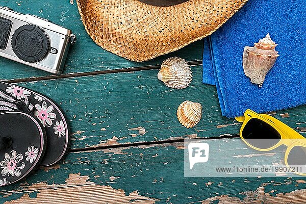 Sommerlicher Hintergrund: Konzept der Freizeitreise im Sommer: Strohhut  Sonnenbrille  Flip Flops  Muscheln  VintageKamera und Badetuch