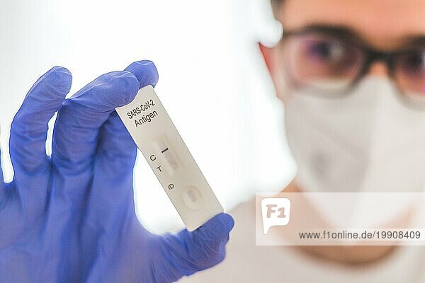 Nahaufnahme des Antigen Corona oder Covid 19 Tests in den Fingern eines jungen Biologen oder Pharmazeuten