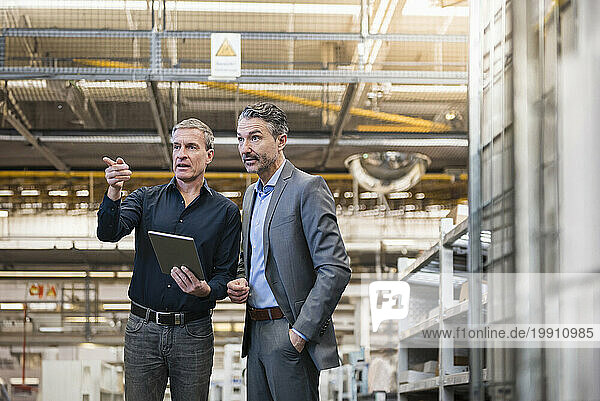 Businessmen having discussion over tablet PC in warehouse