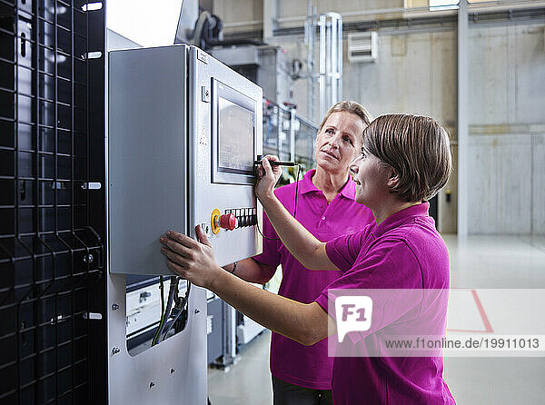 Technicians operating and examining machinery in factory