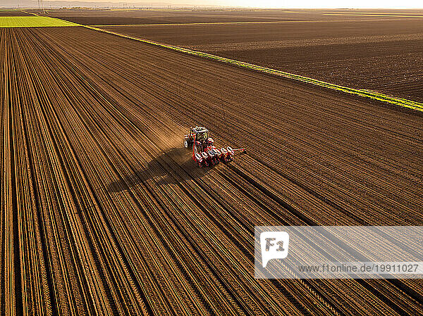 Serbia  Vojvodina Province  Aerial view of tractor sowing seeds in plowed corn field