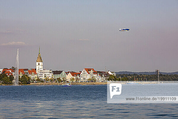 Germany  Baden-Wurttemberg  Friedrichshafen  Blimp flying over city on shore of lake Bodensee at dusk