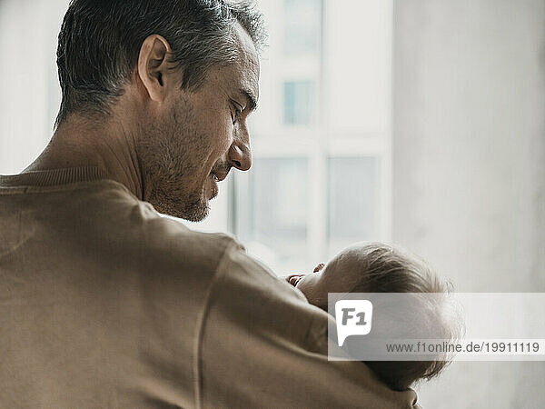 Mature man carrying son at home