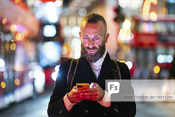 Man using smart phone in city at night