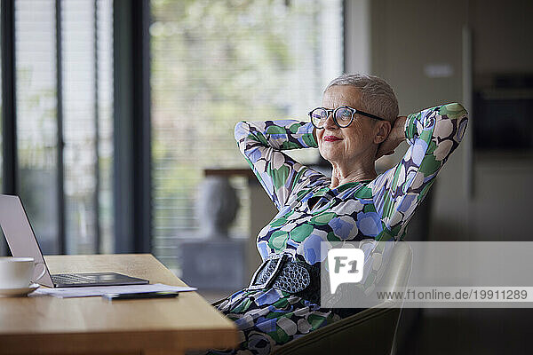 Senior woman with laptop at table leaning back