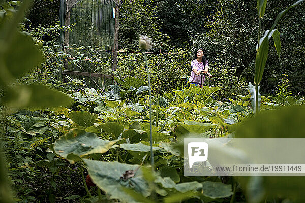 Thoughtful woman standing amidst plants