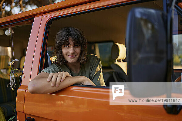 Smiling teenage boy leaning on window of motor home