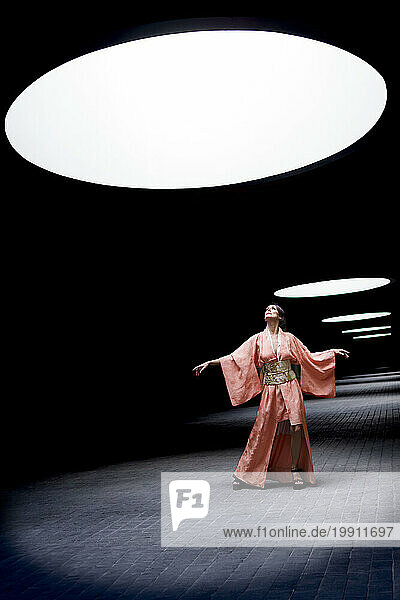 Woman wearing kimono and dancing under spotlight