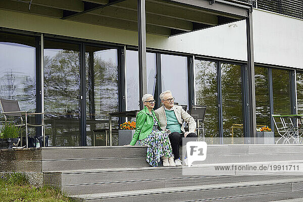 Senior couple sitting on steps in front of their home