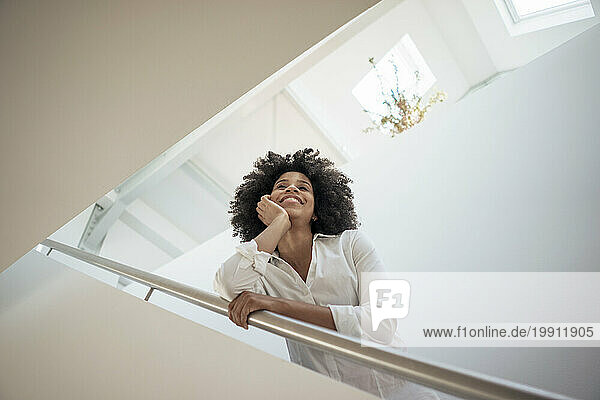 Smiling businesswoman leaning on railing at office