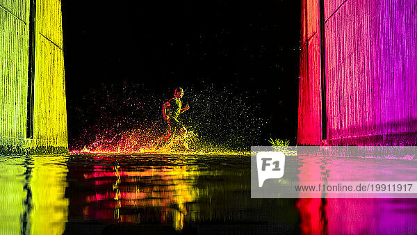 Young man running in river water with neon lights
