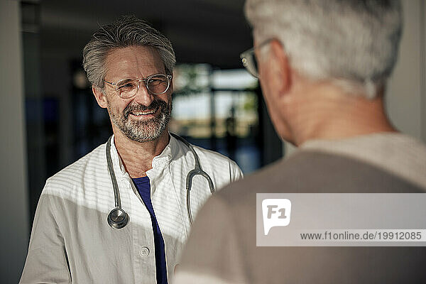 Happy doctor talking to man in hospital