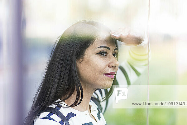 Woman shielding eyes and looking through glass