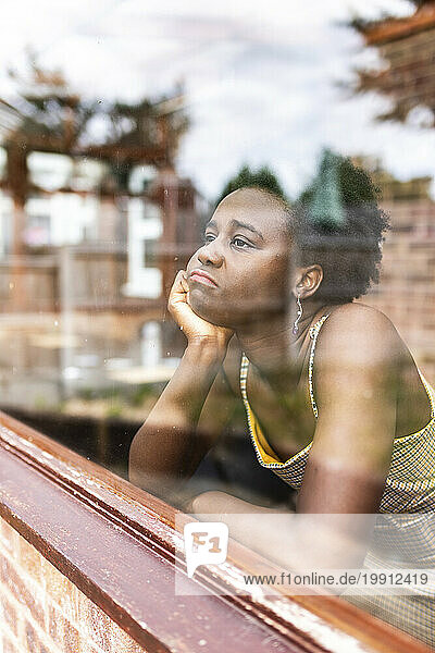 Contemplative woman looking through window
