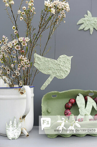 Studio shot of DIY Easter decorations and blooming flowers in enamel jug
