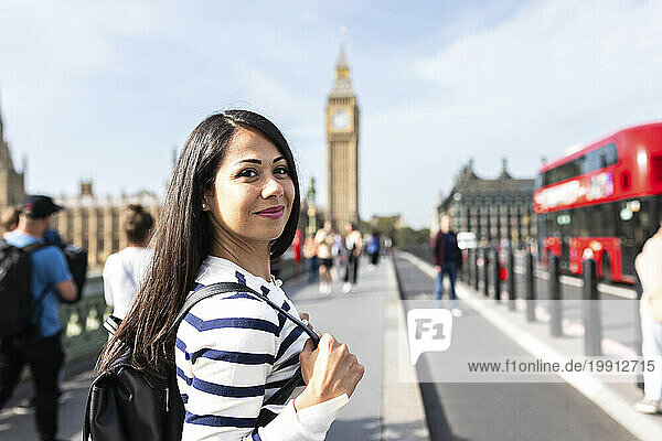 Smiling woman with backpack enjoying vacations in London city