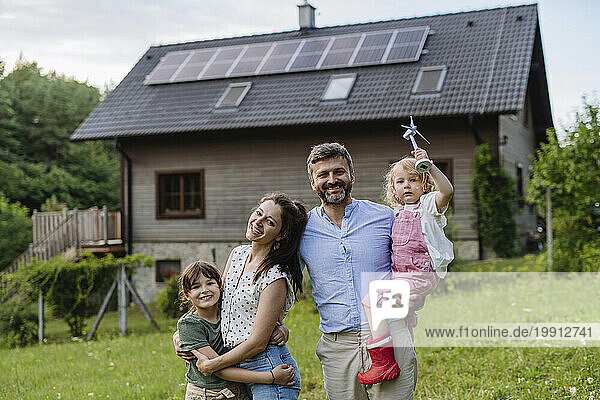 Young family having fun in front their family house with solar panels on the roof