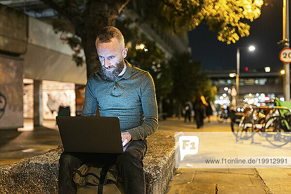 Freelancer working on laptop in city at night