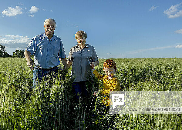 Grandson holding hand of grandparents walking in field