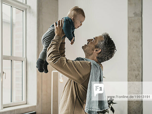 Happy mature man playing with son at home