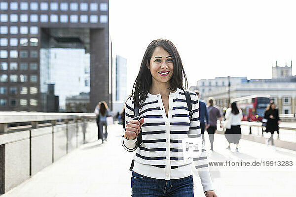 Smiling woman standing on bridge in London city