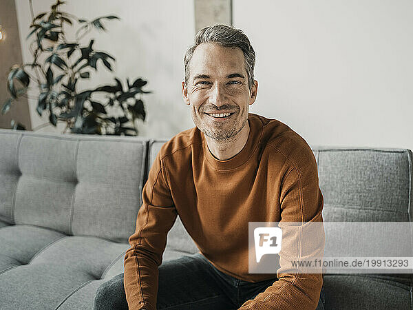 Smiling man sitting on sofa at home