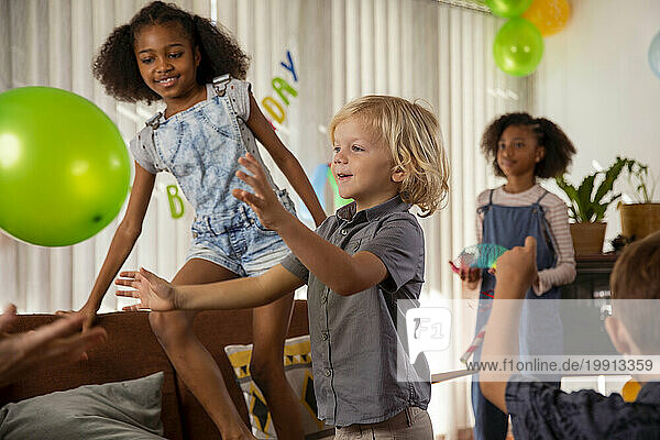 Happy children playing with balloons at home