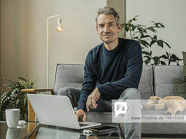 Mature freelancer sitting with laptop at home