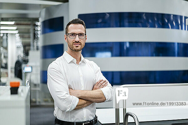 Portrait of a confident businessman at modern machine in a factory