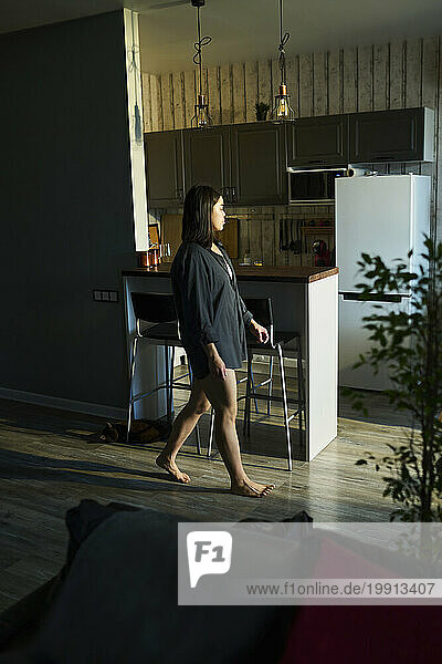 Young woman walking near kitchen at home