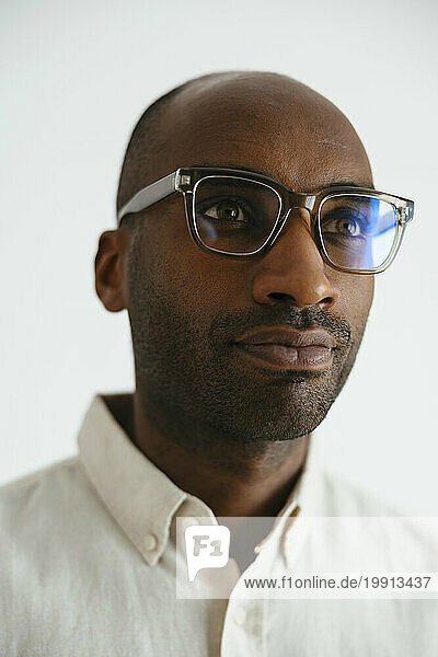 Contemplative man wearing eyeglasses against white background