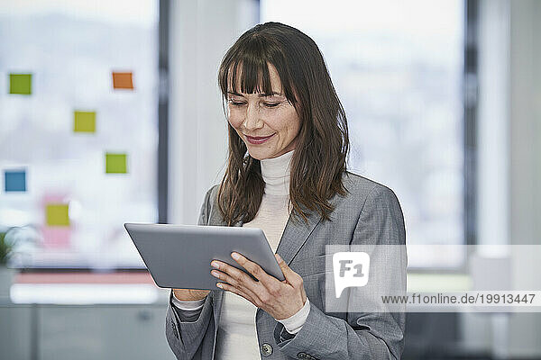 Smiling mature businesswoman using tablet PC in office