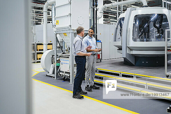 Two businessmen having a meeting at modern machine in a factory