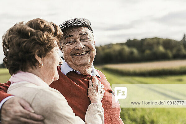 Happy senior couple spending leisure time at field on sunny day