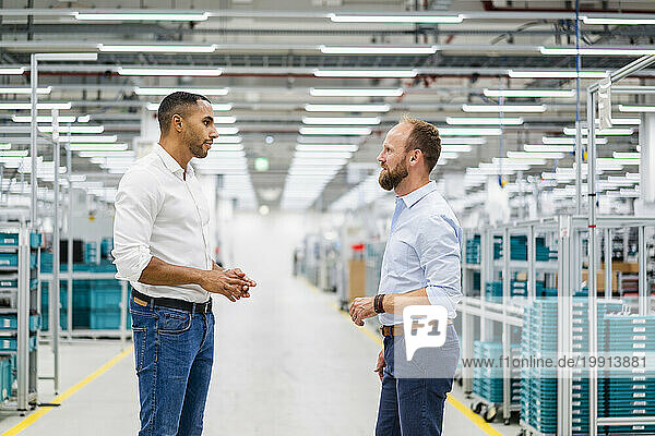 Two businessmen standing and talking in a factory