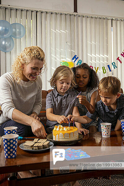 Boy celebrating birthday with mother and friends at home