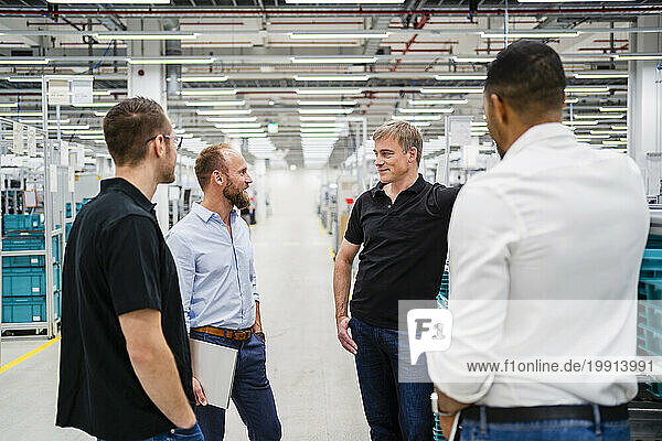 Businessman and employees talking in a factory
