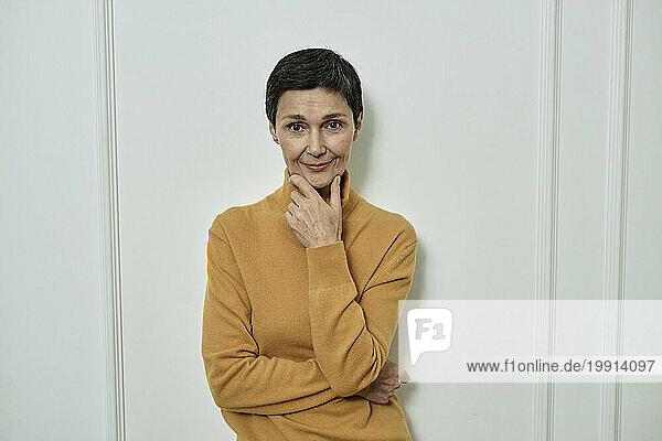 Cheerful adult woman in yellow turtle-neck looking at camera